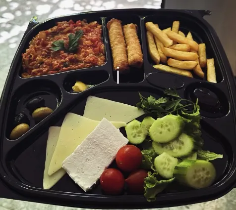 A breakfast tray with cheese, olives, tomatoes and cucumber