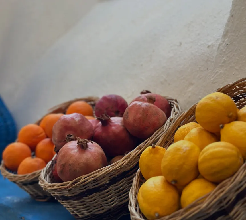 Baskets of oranges, pomegranates and lemons on a blue shelf