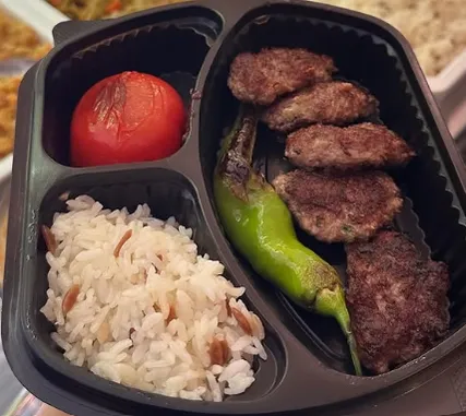 Grilled köfte served with rice, tomato and pepper