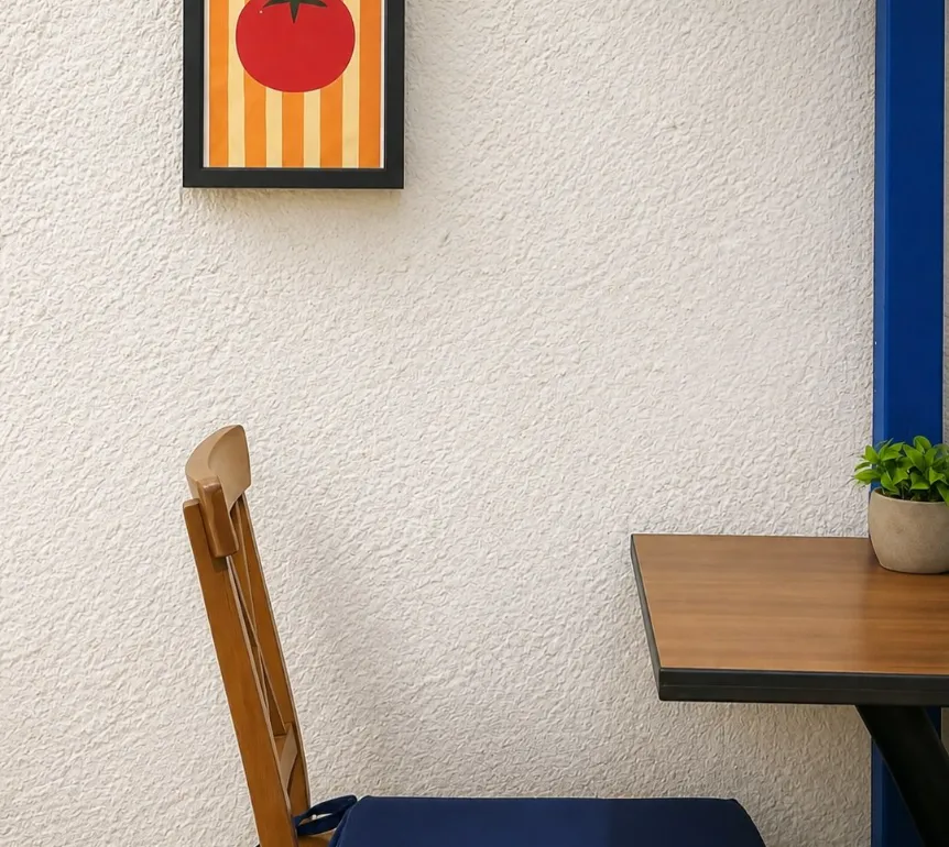 A white wall, blue door frame and wooden table at Dolma