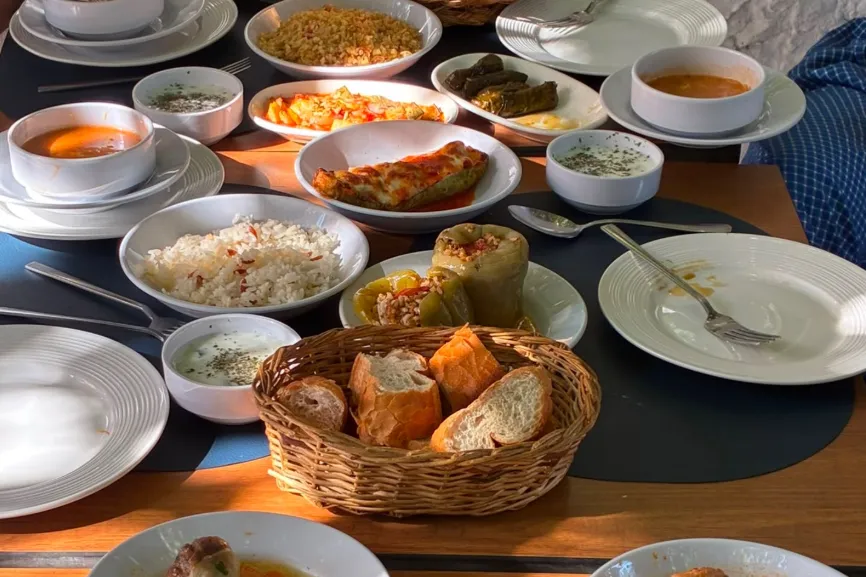 A wooden table at Dolma set with soup, rice, dolma and home-cooked dishes
